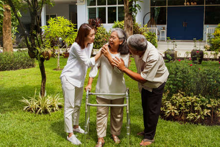 Elderly woman using a walking aid, she fainted, received support from her husband and daughter, used a balm to improve her breathing, expressed concern, and tried to help her best.の写真素材