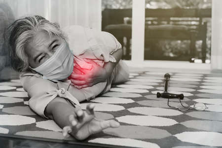 Black and white photo elderly Asian woman collapsed with a face mask with acute heart disease, agonizing pain, reaching for help : Older people who are in poor health have underlying diseases.の写真素材