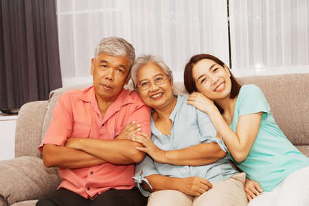 Portrait asian family happy sitting together on sofa at home : Elderly parents and daughters bond care for life together in retirement age.の写真素材