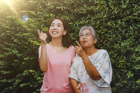 The millennial mother had a healthy and positive attitude, with her daughter taking a walk in the park together, pointing to the light fair from the afternoon sun with excitement.の写真素材