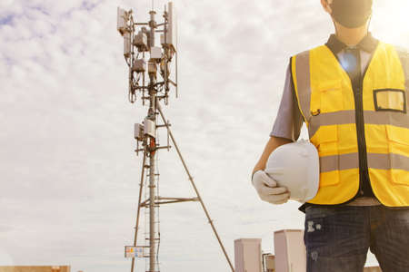 Male technician engineers wearing safety protective clothing work high tower telecommunication antennas installed on buildings for construction, installation and general maintenance work.の写真素材
