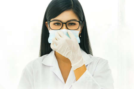Portrait Scientific researcher of beautiful Asian women wearing masks and taking care neatness to enter the laboratory in the laboratory.の写真素材