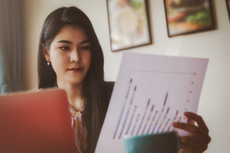 Portrait beautiful businesswoman working in her home, office, looking at graphs, financial markets, her business and paying much attention.の写真素材