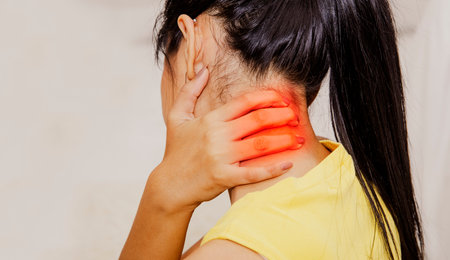 Back view Woman pain in the back of the neck, degeneration of the neck, moving over the nerve. Or spinal cord, is using a hand massage to relieve pain.の写真素材
