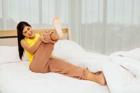 Concept health care : Young woman suddenly had muscle pain in her thighs from cramps while she slept in bed.の写真素材