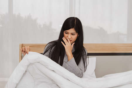 Concept health care : Woman had a runny nose, stuffy nose, cough, sneezing, sore throat due to dust allergies from dirty blankets, dust mite allergy symptoms.の写真素材