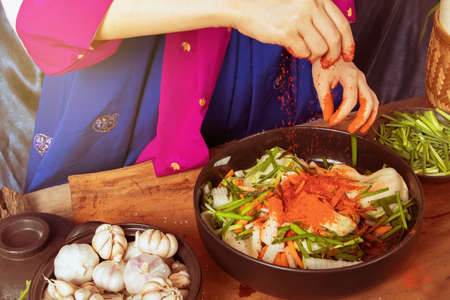 Top view Cooked pickled kimchi, a Korean traditional dish by a young woman wearing a hanbok, using quality ingredients mixed with chili and fresh vegetables : Pickled vegetables, kimchi conceptの写真素材