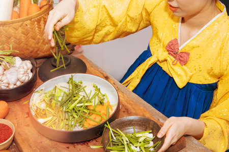 Young Korean women in golden hanbok cook traditional kimchi dishes using fresh and quality ingredients and ingredients : Pickled vegetables, kimchi conceptの写真素材