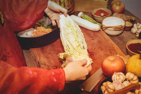 Women wearing red Hunbok clothes select fresh white cabbage and prepare to make kimchi.Chinese cabbage on a cutting board, Khun Thapdee, ingredients, steps, recipe, traditional homemade kimchiの写真素材
