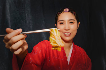 Shoot stunning portrait of a woman wearing red Korean hanbok looks at the delicious traditional white cabbage, pickles,kimchi : Asian women pride themselves on Chinese cabbage, homemade kimchi recipe.の写真素材