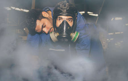 Technician wears an NH3 ammonia protective mask to help an unconscious colleague suffocate urgently due to the violent ammonia gas leaking in the work area in the frozen food industry :Selective focusの写真素材