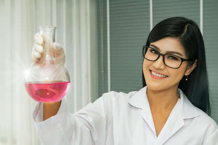 Portrait young Asian scientist holds a test tube containing an important compound as a sample and is tested or researched in a clinical laboratory.の写真素材