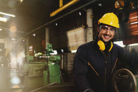 Portrait of an Arab worker working as a technician in an industrial factory abroad Happy Smiling handsome technician worker, hearing protection headphones and safety helmet on the head for safety.の写真素材