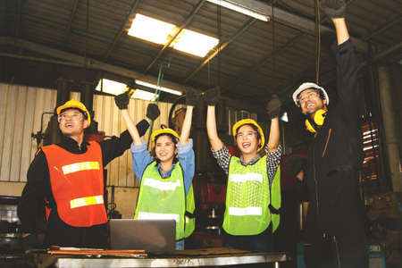 Male engineer wearing a white safety helmet shows leadership to the technician team, the male and female workers show solidarity, and all agree to be happy to work together.の写真素材