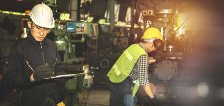 Male engineer foreman inspects the machine parts that the female worker technician has built, preliminary inspection and evaluation of the work, and to meet the standardsの写真素材