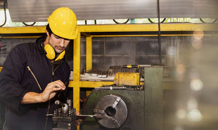 Asian Indian engineer machinist in factory inspects lathe blades, prepares lathe for equipment alignment. Lathe Industry Factory : factory safetyの写真素材
