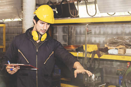 Indian industrial engineer worker technician wearing safety suit and hard hat works according to the detailed design specification in the metal fabrication lathe clipboardの写真素材