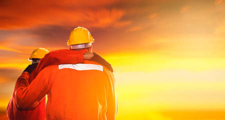 Back view engineers, machinists and factory workers working together look at the sunset sky, showing support, empathy and understanding, encouraging each other : Positive support concept : Copy Spaceの写真素材