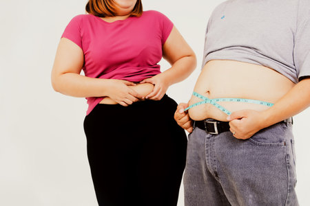 Couples with obese and obese sizes squeeze excessive waist and use a waist tape to compare their excess fat : Concept Obesity of men and women who are not healthy.の写真素材