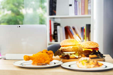 Appetizing lunch, two large pork hamburgers, pizza, fried chicken thighs in the office at home.