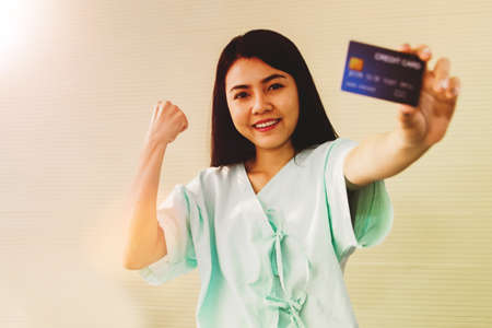 Happy perfect, young asian female patient presents a health insurance credit card for medical treatment without worrying about hospital costs : Love myself health insurance service conceptの写真素材