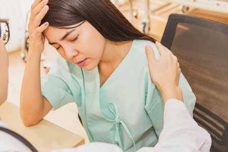 Asian female patient discouraged Desperate and despairing from a serious chronic disease Being hospitalized,receiving encouragement,touching the shoulder, comforting care from a male doctor who treatsの写真素材