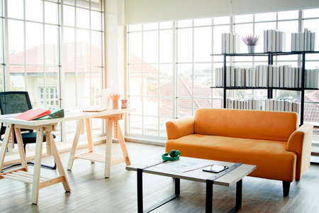 Distant view : Translucent glass room, home office in the living room with bookshelves, and cozy vintage  trendy Orose-style sofas.の写真素材