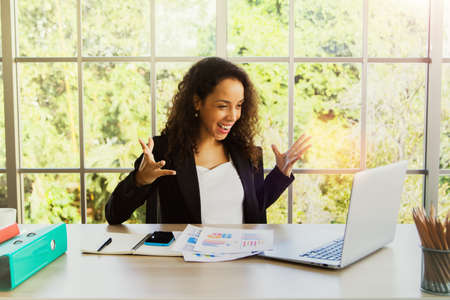 Business woman sittingenjoy : Portrait happy hipster woman millennial businesswoman posing smiling cheerfully happy when she reads messages on her laptop in a good mood in the modern office room.の写真素材