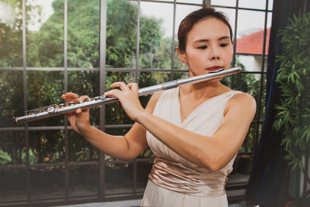 Asian female artist superstars perform flute music with deep classical melodies in a tranquil setting : Young woman with musical talent with a flute instrument.の写真素材