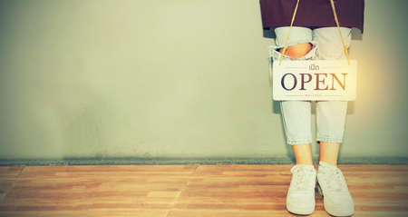 Closed for business : Woman standing holding a white wooden sign with a message saying it is closed : Coffee shop service during the coronavirus outbreak covid-19 has a negative impact on the businessの写真素材