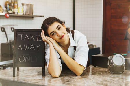 Portrait beautiful female barista sitting in front of the barista smiling charming at camera at the coffee shop : Pretty girl, small business owner, coffee business Conceptの写真素材