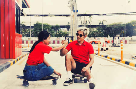 Asian couples take a break and relax on the street after skateboarding in the outdoor sport of active Thai teenagers.の写真素材