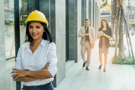 Happiness of a beautiful architect, working in the field with a team of businessmen and businesswoman planning outside the building.の写真素材