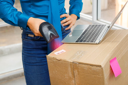 Online delivery concept : Businesswoman checks goods in a warehouse using a barcode scanner electronic. Marking labels, boxes, parcels for shipping logistics distribution center for customers.の写真素材