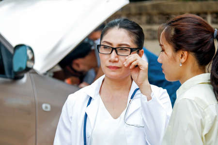 Doctor and a female assistant are worried during a broken car on the way to treat a patient outside the facility : Accidents and Unexpected Events concept.の写真素材