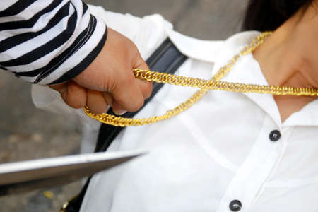 Crime concept : Robbery stealth : Thieves use knife weapons to hurt women in order to steal a gold chain necklace.の写真素材