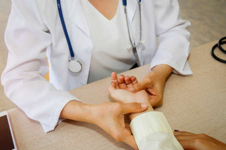 Pulse Detection on wrist : Female doctors monitor the heart rate of female patients and their symptoms.の写真素材