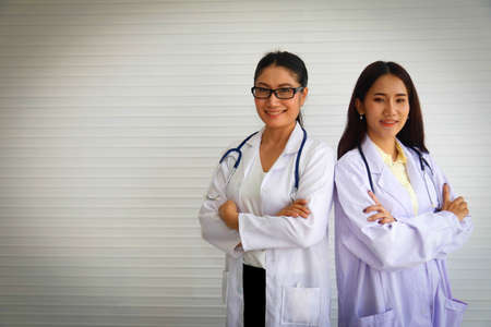 Team two female doctors in white medical uniforms and stethoscope : Senior female doctors and medical students stand ready to give advice and consult in the hospital.の写真素材