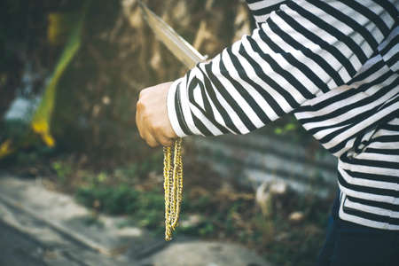 Homeless robbers carry weapons with a knife to commit a crime by robbing a gold necklace from the victim and running away on a road : Copy Spaceの写真素材