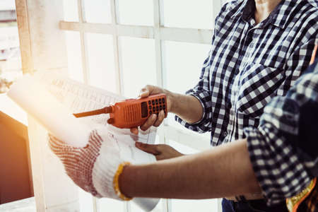 Female engineers are working on building field blueprint projects, teaching workers, and using radios to work at construction sites to increase efficiency.の写真素材