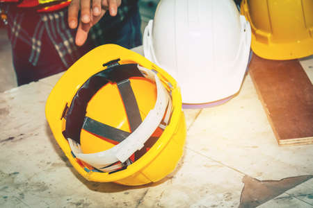 Workers are using their hands to pick up a yellow helmet. Upside down on the wooden table to use.の写真素材