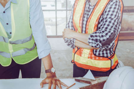 Planning for the work of two engineers, men and women, discussing together, according to the field work area, wearing a safety vestの写真素材