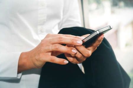 Hands of businesswoman searching for Internet messages on a modern touchscreen smartphone are part...