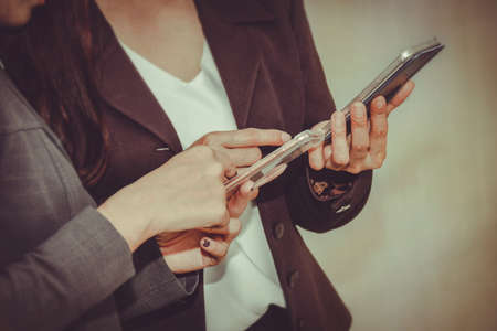 Two business women use their screen smartphones to highlight the importance of  network modern communication and to focus on the touchscreen applications in their new phones mobile .の写真素材