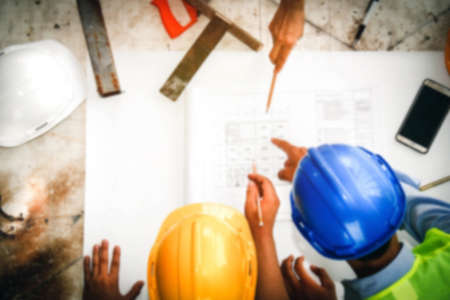 Blurry image group of architects, engineers and industrial men work together for a brainstorming team on their desks to discuss a construction project on the site.の写真素材
