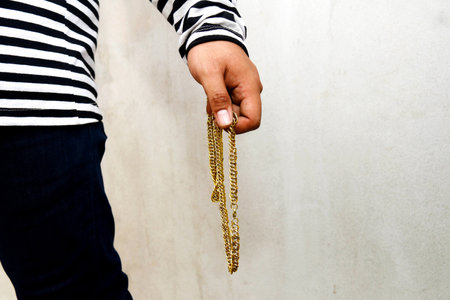 Crime concept : Male thief shows up holding a gold necklace and commits a serious crime of extorting property.の写真素材