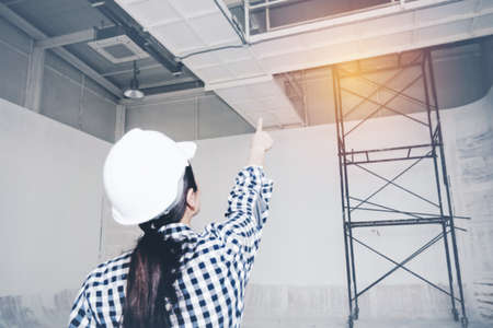 Blurred photo back of the female architect examines the field work in the incomplete construction area and points upwards, which is the point that must be fixed for safety : Blurred backgroundの写真素材