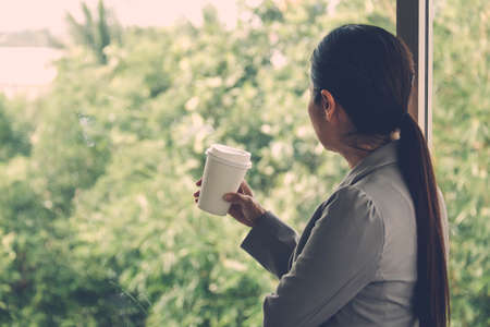 Concepts stand alone : Businesswoman standing in awe at the mirror, looking out the window in the office. Soft focusの写真素材