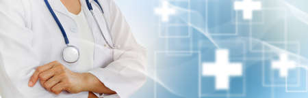 Health and medical insurance concept : Female doctor folded arms with medical stethoscope standing start-up confident in treating patients abstract blur background.の写真素材