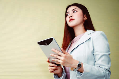 PortraitAsian business woman using a laptop in a casual office room looking at the outside.の写真素材